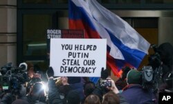 FILE - Former adviser for President Donald Trump, Roger Stone, is surrounded by protesters and supporters, some with signs and Russian flags, as he arrives at federal court in Washington, Jan. 29, 2019.