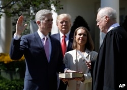 President Donald Trump watches as Supreme Court Justice Anthony Kennedy administers the judicial oath to Judge Neil Gorsuch during a re-enactment in the Rose Garden of the White House White House in Washington, April 10, 2017.
