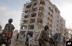 An African Union (AU) soldier walks past the scene of destruction following a suicide car bomb attack in the capital Mogadishu, Somalia, July 26, 2015.