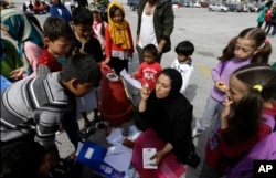 University teacher Ziaee Shole, center, speaks to Afghan children at the Athens port of Piraeus, on April 1, 2016.