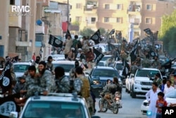 FILE - Fighters from the Islamic State group parade in Raqqa, north Syria, June 30, 2014. A former British spy chief said at the time that militants had more than doubled the recruitment of foreign fighters to as much as 31,000 over the previous 18 months.