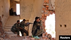 FILE - Kurdish People's Protection Units (YPG) fighters take up positions inside a damaged building in al-Vilat al-Homor neighborhood in Hasaka city, Syria, as they monitor local movements of Islamic State fighters.