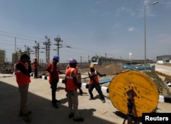 Laborers pull a wire from a spool near a Hyundai Rotem train inside the Delhi Metro Rail Corporation (DMRC) Mukundpur depot in New Delhi, India, April 6, 2016.