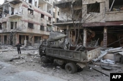 FILE - A Syrian man pauses near destruction following a reported regime air strike in the rebel-held town of Hamouria, in the besieged Eastern Ghouta region on the outskirts of the capital Damascus, Feb. 21, 2018.