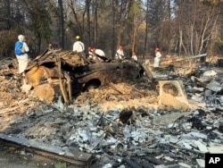Volunteer members of an El Dorado County search and rescue team search the ruins of a home and vehicle, looking for human remains, in Paradise, Calif., Nov. 18, 2018, following a Northern California wildfire.