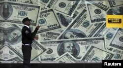 A security guard walks past a montage of old U.S. dollar bills outside a currency exchange bureau ahead of a scheduled State visit by the U.S. President Barack Obama in Kenya's capital Nairobi, July 23, 2015.