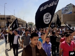 FILE - Demonstrators supporting the Islamic State of Iraq and the Levant (ISIL) carry al-Qaida flags in front of the provincial government headquarters in Mosul, Iraq, June 16, 2014.