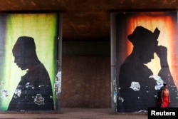FILE - A woman stands in front of a poster in Bamako, Mali, Feb. 21, 2014.