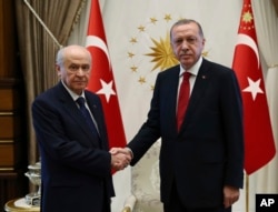 FILE - Devlet Bahceli, left, leader of the Nationalist Movement Party, or MHP, and the main ally of Turkey's President Recep Tayyip Erdogan, right, shake hands before a meeting at the presidential palace in Ankara, June 27, 2018.