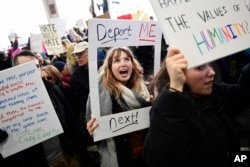 FILE - Madison Gray, a Temple University student, holds up her sign during a protest against President Donald Trump's executive order banning travel to the U.S. by citizens of Iraq, Syria, Iran, Sudan, Libya, Somalia or Yemen, Jan. 29, 2017, at Philadelphia International Airport in Philadelphia.