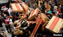 Shoppers reach for television sets as they compete to purchase retail items on Black Friday at a store in Sao Paulo, Brazil, Nov. 24, 2016.