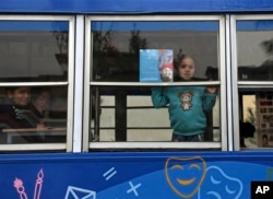 Children look out the window of a library on wheels, in Kabul, Afghanistan, March 10, 2018.