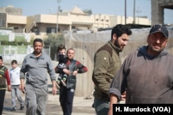 Mahmoud Abd (R) and his neighbors say they continue to be sickened by the smell from a nearby suspected chemical bomb and they still don't know exactly what was in it, in eastern Mosul, Iraq, March 8, 2017.