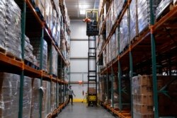 Workers shout to each other from five levels of stored food items at the warehouse of The Capital Area Food Bank, in Washington, Oct. 5, 2021.