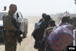 Ahmed Ghalibi from Iraq’s Emergency Response Unit media team directs families toward trucks waiting to carry them to hospitals and refugee camps, Feb. 26, 2017. (H. Murdock/VOA)