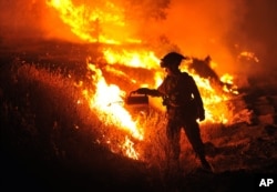 California firefighter Bo Santiago watches a backfire as the Rocky fire burns near Clearlake, California, Aug. 3, 2015.