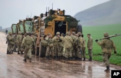 Turkish Army soldiers form a convoy of armored personnel carriers near the border with Syria, in the outskirts of Hassa, Turkey, Jan. 23, 2018.