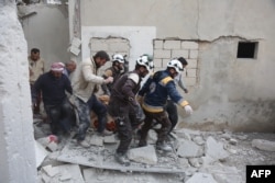 Members of the Syrian Civil Defence (also known as "The White Helmet") carry a wounded person following reported shelling in the town of Khan Sheikhun in the southern countryside of the rebel-held Idlib province, Feb. 26, 2019.