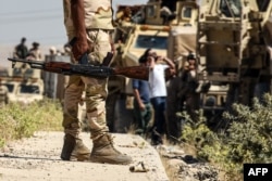 FILE - Iraqi government forces drive down a road leading to Tal Afar, June 9, 2017, during ongoing battles to retake the city from Islamic State fighters.