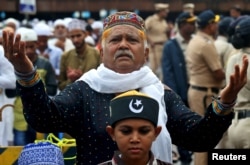 FILE - A man offers Eid al-Fitr prayers marking the end of the holy fasting month of Ramadan outside a railway station, in Mumbai, India, June 16, 2018.