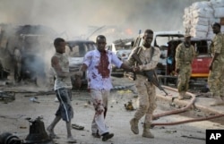 FILE - A Somali soldier helps a civilian who was wounded in a blast in the capital of Mogadishu, Somalia, Oct. 14, 2017.