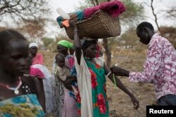 FILE - A mother carrying her baby in a basket is screened for malnutrition at a joint UNICEF-World Food Program Rapid Response Mission, which delivers critical supplies and services to those displaced by conflict, in Nyanapol, South Sudan, March 3, 2015.