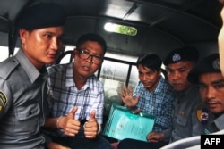 FILE - Myanmar journalists Wa Lone, (L) and Kyaw Soe Oo (3rd-R) are escorted by police from the courthouse as they are taken to prison after the first day of trial in Yangon, July 16, 2018.