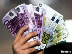An activist shows fake banknotes during a demonstration outside the European Commission (EC) headquarters ahead of statements by the EC on the effectiveness of existing measures against tax evasion and money-laundering in light of the recent Panama Paper revelations, in Brussels, Belgium, April 12, 2016.