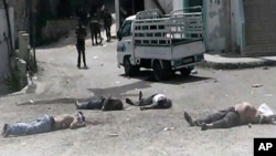 This citizen journalist image provided by The Syrian Revolution against Bashar Assad, which has been authenticated based on its contents and other AP reporting, shows Syrian army soldiers standing in front of dead bodies at Bayda village.