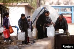 FILE - People queue as they fill containers with water in the government controlled al-Rabwah area, a suburb of Damascus, Jan. 10, 2017.