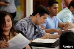 FILE - Ernesto Delgado, center, a Deferred Action for Childhood Arrivals recipient, fills out his renewal application at Lincoln Methodist Church in Chicago, Sept. 10, 2017. DACA recipients gathered to fill out applications