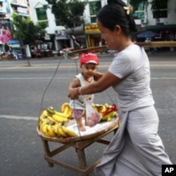 A street vendor carries her son and bananas on a street in Rangoon.