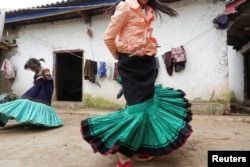 A Yi ethnic minority girl Jisi Mewuzuo (R) and her sister Jisi Meyouzuo dance holding traditional Yi skirts in Butuo County, Sichuan province, China, July 19, 2017.