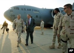 US Defense Secretary Donal Rumsfeld, center, speaks with US Army General George Casey, second from left, upon arriving at Baghgad International Airport, April 26, 2006.