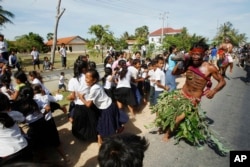 FILE - A local youth, front right, scares pupils on a street as he takes part in a ceremony to exorcize evil spirits and pray for rain amid the rice planting season at Pring Ka-ek village, northwest of Phnom Penh, Cambodia, May 22, 2015.