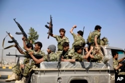 FILE - Shi'ite fighters, known as Houthis, ride on a patrol truck as they chant slogans during a tribal gathering showing support for the Houthi movement in Sanaa.