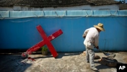 FILE - A church member shovels cement mix preparing to re-mount a cross on a Protestant church, which had been forcibly pulled down by Chinese government workers in Taitou Village, eastern China, July 29, 2015.