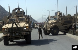 FILE - A U.S. soldier directs his colleagues at the site a bomb attack that targeted several armored vehicles belonging to forces attached to the NATO Resolute Support mission in downtown Kabul, Oct. 11, 2015.
