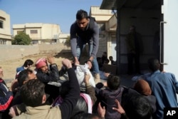 FILE - Residents of a neighborhood recently liberated from Islamic State militants gather for humanitarian aid in the eastern side of Mosul, Iraq, Jan. 11, 2017.