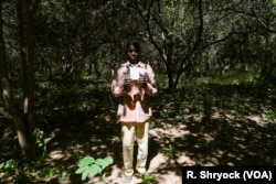 Ibrahima Ingo, a refugee from Senegal now living in Guinea-Bissau, holds up his citizenship registration as he stands in his cashew field in Pelundo, Nov. 11, 2018.