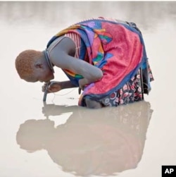 Feb. 6, 2010. Kuse Dam, Terekeka County, Southern Sudan. A young herder in Kuse Dam uses a pipe filter provided by The Carter Center to strain out infective Guinea worm larvae from the water while drinking.