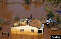 A man looks around from atop his house after Cyclone Idai in Buzi district outside Beira, Mozambique, March 22, 2019.