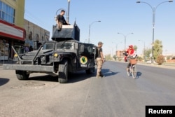 A cyclist gestures at Iraqi security forces, on a street of Kirkuk, Iraq, Oct. 19, 2017.