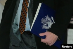 A member of the U.S. trade delegation to China, carries a folder as he leaves a hotel in Beijing, Jan. 7, 2019.