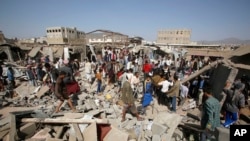 People gather on the rubble of shops destroyed by a Saudi-led airstrike at a market in Sana'a, Yemen, July 20, 2015.