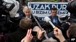 Campaign staff hold a banner reading "Stay Away, This Is Our Country" as firebrand anti-Islam lawmaker Geert Wilders, left, protests outside the Turkish embassy in The Hague, Netherlands, March 8, 2017.