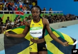 Jamaica's Elaine Thompson celebrates with the Jamaican flag after winning gold in the women's 100-meter final during the athletics competitions in the Olympic stadium of the 2016 Summer Olympics in Rio de Janeiro, Brazil, Saturday, Aug. 13, 2016.