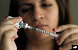 FILE - A woman fills a syringe as she prepares to give herself an injection of insulin.