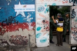 A National Guard soldier frisks a man before allowing him inside a polling station during regional elections in Caracas, Venezuela, Oct. 15, 2017.