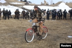 A man rides a bicycle away from the police as they attempt to clear the Oceti Sakowin camp, Feb. 23, 2017.